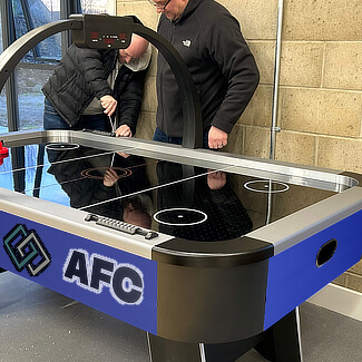 Two men prepare a branded air hockey table for play.