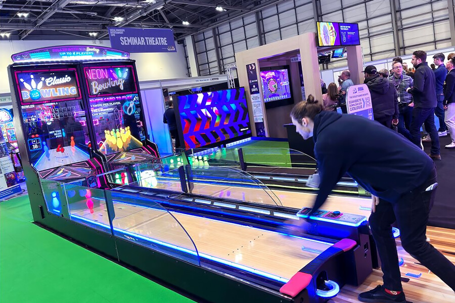 People playing the Neon Bowling arcade machine.