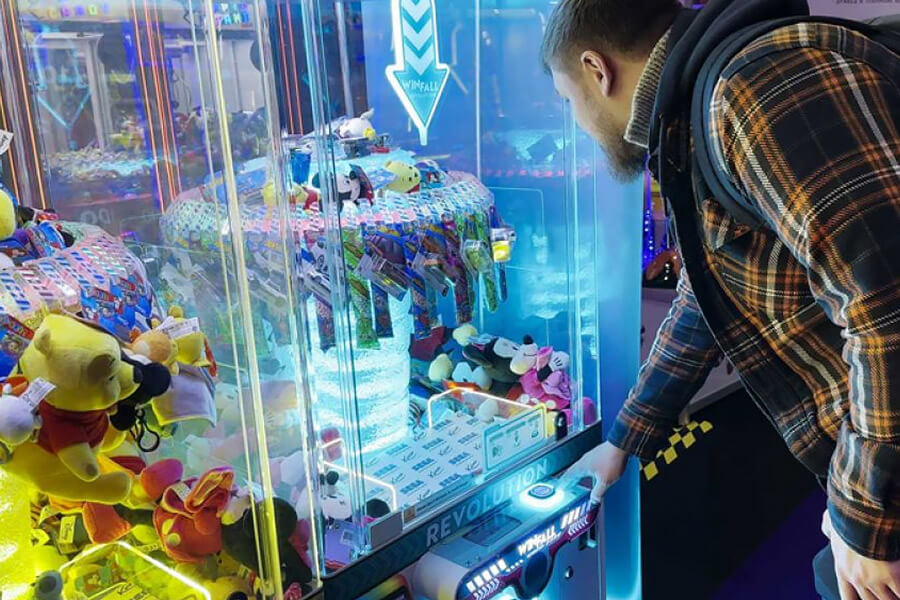 Person playing Win Fall Revolution arcade machine.