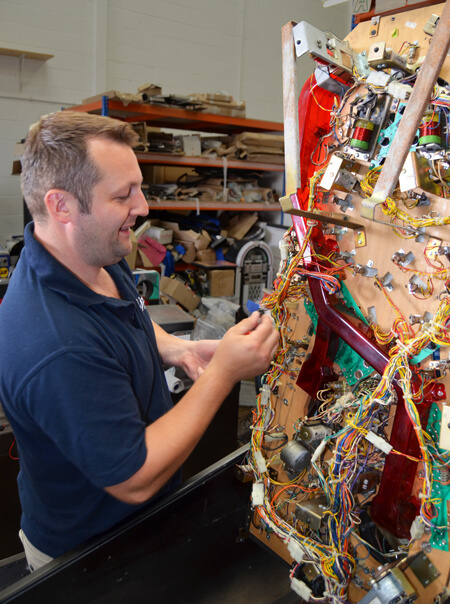 A technician restoring a classic pinball machine.