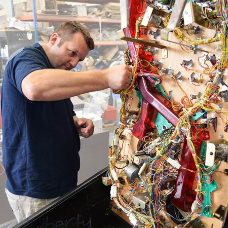 A technician working on a reconditioned pinball.