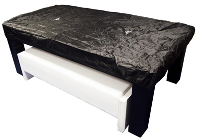 A pool table protected with a dust cover.