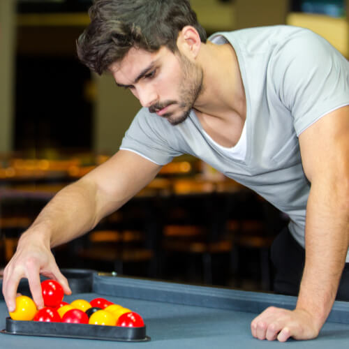 A man sets up the balls on a pool table.