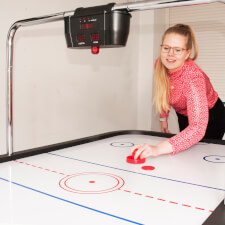 A girl playing Sure Shot Championship Air Hockey.