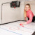 A girl playing Sure Shot Championship Air Hockey.