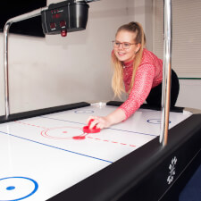 A girl playing Sure Shot Super Pro Air Hockey.