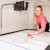 A girl playing Sure Shot Super Pro Air Hockey.