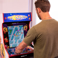 Man playing Arcade1up Bandai Namco Pac-Mania legacy arcade machine.