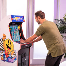 Man playing Arcade1up Bandai Namco Pac-Mania legacy arcade machine.