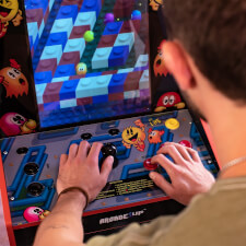 Man playing Arcade1up Bandai Namco Pac-Mania legacy arcade machine.