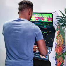 Man playing Arcade1up Atari legacy Centipede arcade machine.