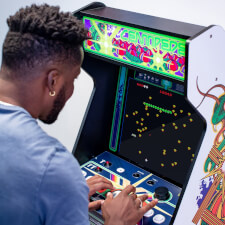 Man playing Arcade1up Atari legacy Centipede arcade machine.