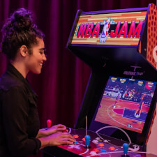 Girl playing Arcade1Up NBA Jam machine.