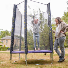 Kid bouncing on the Plum Junior Stardust Springsafe trampoline with enclosure.