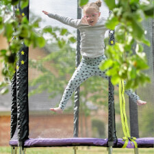 Kid bouncing on the Plum Junior Stardust Springsafe trampoline with enclosure.