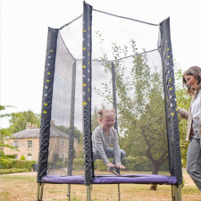 Kid bouncing on the Plum Junior Stardust Springsafe trampoline with enclosure.