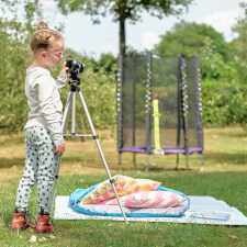 Kid playing Plum Junior Stardust Springsafe trampoline with enclosure.