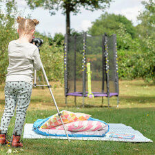 Kid playing Plum Junior Stardust Springsafe trampoline with enclosure.