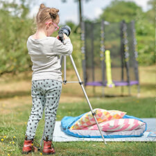 Kid playing Plum Junior Stardust Springsafe trampoline with enclosure.