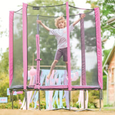 Kid jumping on the Plum 6ft junior Springsafe trampoline and enclosure in pink.