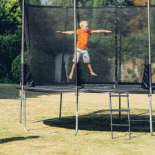 Kid bouncing on the Plum Space Zone II Springsafe trampoline with enclosure.