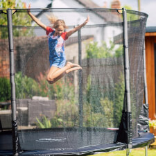 Kid jumping in the Plum Space Zone II Evolution  Springsafe Trampoline and enclosure.