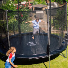 Kid jumping in the Plum Space Zone II Evolution  Springsafe Trampoline and enclosure.