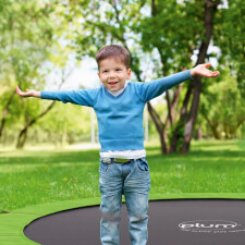 Kid bouncing on the Plum In-Ground Springsafe Trampoline and enclosure.