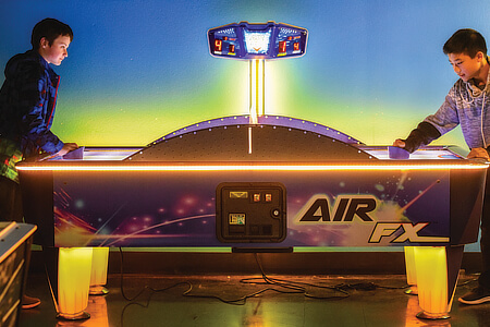 An air hockey table being played at a youth club.