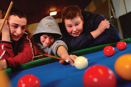 A pool table being played at a youth club.