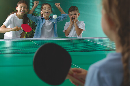 A table tennis table being played at a youth club.